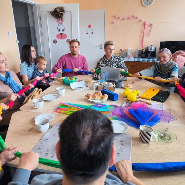 Osoby przy stole robią kolorowe lanyrdy.